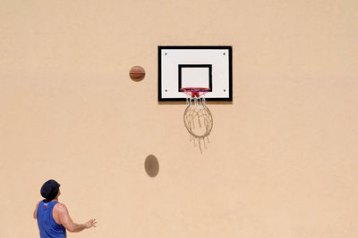 Man with basketball hoop against wall