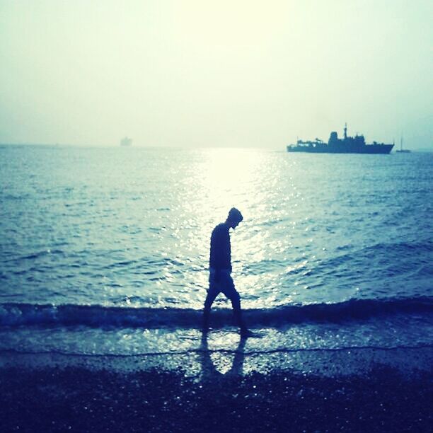 water, sea, silhouette, full length, horizon over water, standing, lifestyles, leisure activity, rear view, tranquility, tranquil scene, men, sky, scenics, nature, beauty in nature, clear sky, shore