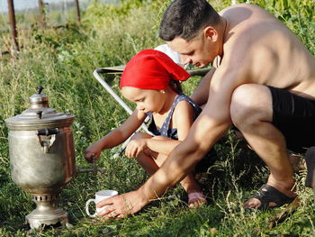 A little girl, while relaxing with her dad in nature, learns to pour tea from a family affairs 