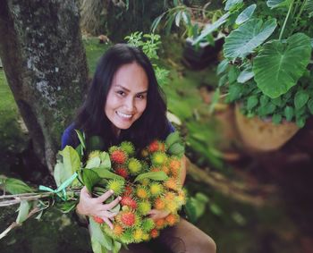 Portrait of smiling woman holding rambutans