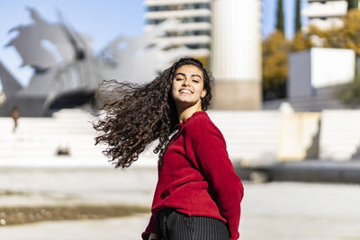 Portrait of smiling teenage girl standing in city