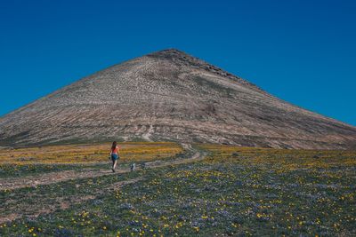 Full length of man climbing on land against clear blue sky