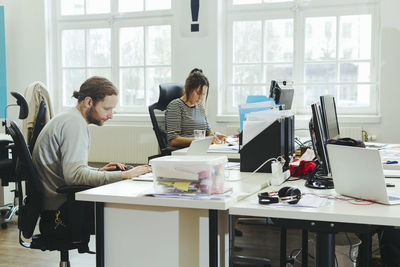 Business colleague working at computer desk in creative office