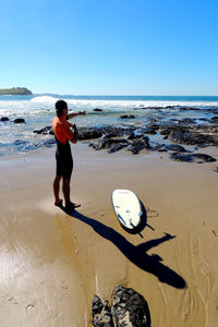 Full length of man with surfboard standing on beach