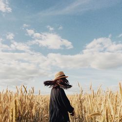 Woman standing in wheat field against sky