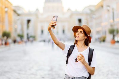 Portrait of smiling young woman standing in city