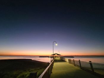 Street by sea against sky during sunset