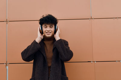 Portrait of young woman standing against yellow wall