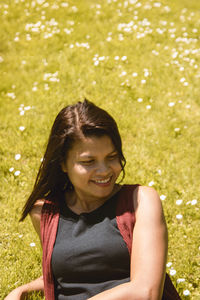 High angle view of smiling young woman relaxing on grassy field