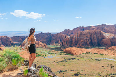 Rear view of woman standing on mountain against sky