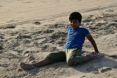 Portrait of boy sitting on sand at beach