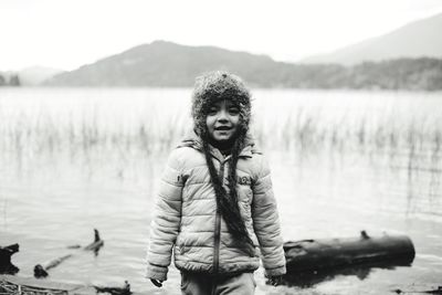 Portrait of girl wearing warm clothing while standing against lake
