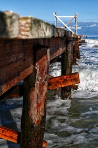 Close-up of wooden boardwalk by sea against sky