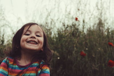 Close-up portrait of girl smiling against plants