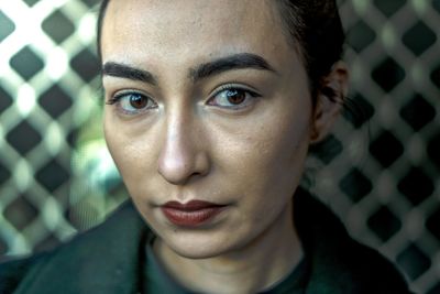 Close-up portrait of woman against fence