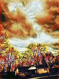 Low angle view of trees and houses against sky