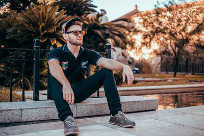 Full length portrait of young man sitting outdoors