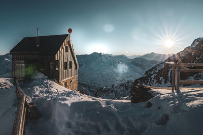 Snow covered houses by buildings against sky during winter