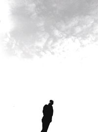 Silhouette man on rock against sky