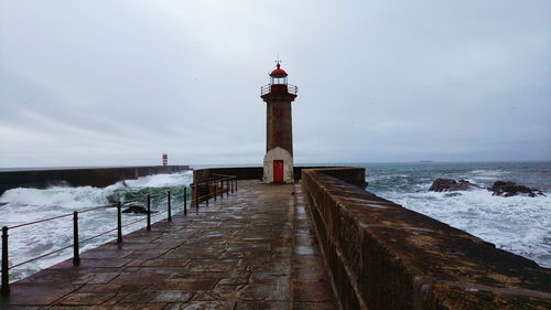 Lighthouse amidst sea and buildings against sky