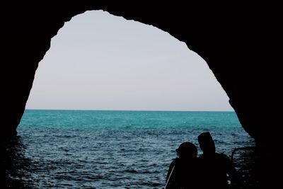 Rear view of silhouette people standing by sea against clear sky