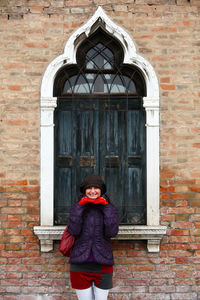Portrait of woman standing against window during winter