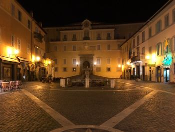 Illuminated street amidst buildings in city at night