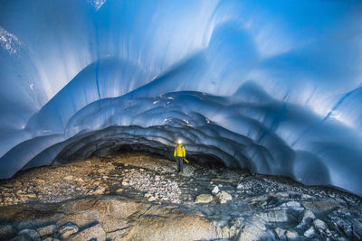 Mountaineer standing in glacial cave.