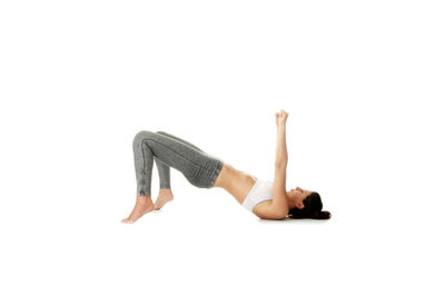 Side view of young woman relaxing against white background