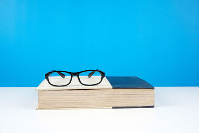 Close-up of eyeglasses on book against blue background