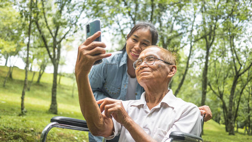 Portrait of man photographing with mobile phone in park