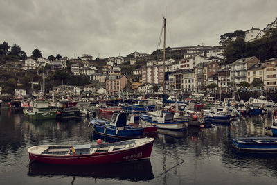 Boats moored at harbor by buildings in city