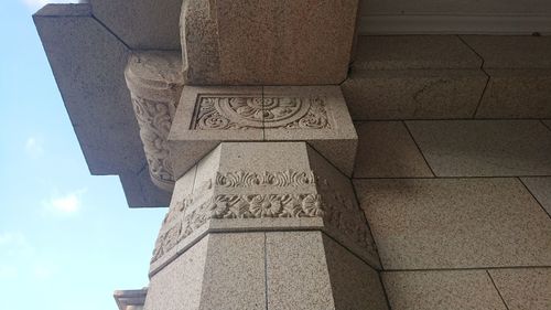 Low angle view of cross column against sky