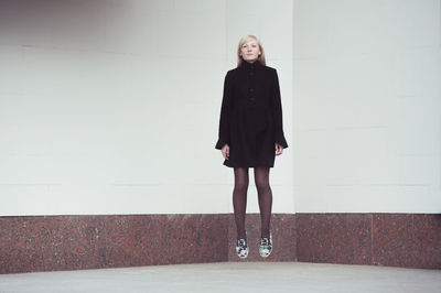 Levitation of young woman against wall