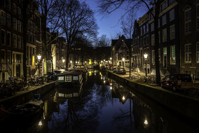 Canal amidst buildings in city at night