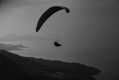 Silhouette person paragliding against sky