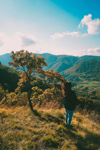 Rear view of person standing on landscape against sky