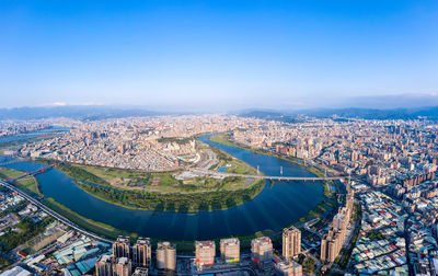 High angle view of city buildings against blue sky