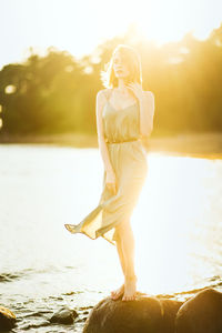 Woman wearing hat against lake during sunset