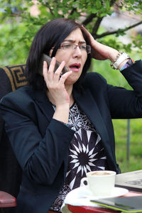 Young woman using mobile phone while sitting outdoors