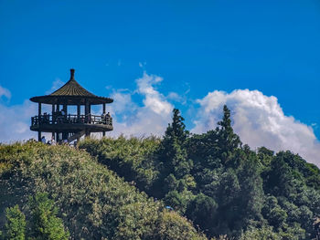 Traditional building by trees against blue sky