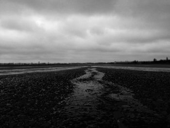 Road passing through landscape against cloudy sky