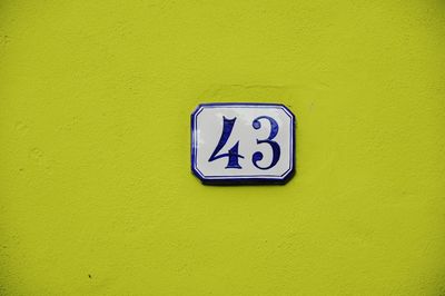 Close-up of sign on yellow wall