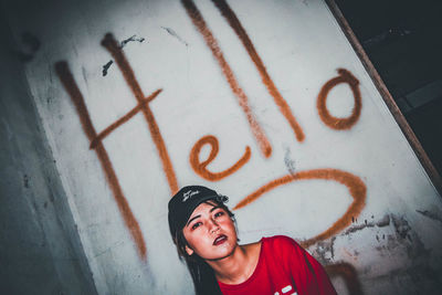 Portrait of smiling man standing against graffiti wall