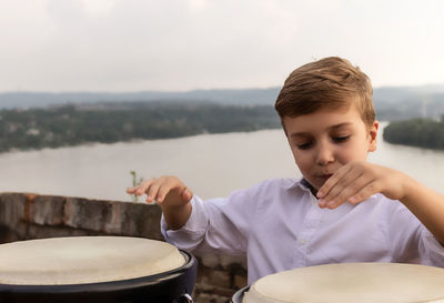 Little drummer playing bongos at riverside.