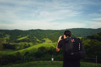 Rear view of woman standing on mountain against sky