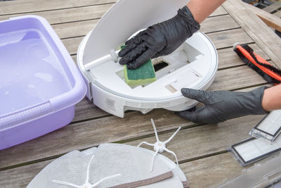 Woman washing a trash can in a robot vacuum cleaner, planned maintenance