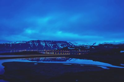 View of illuminated city against cloudy sky at night