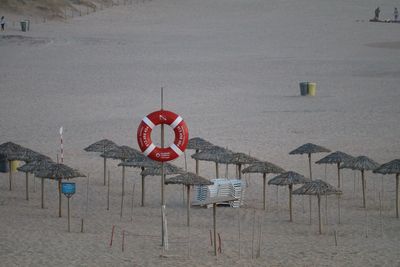 High angle view of life belt hanging on pole by straw parasols at beach