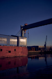 Built structure by sea against clear blue sky at dusk